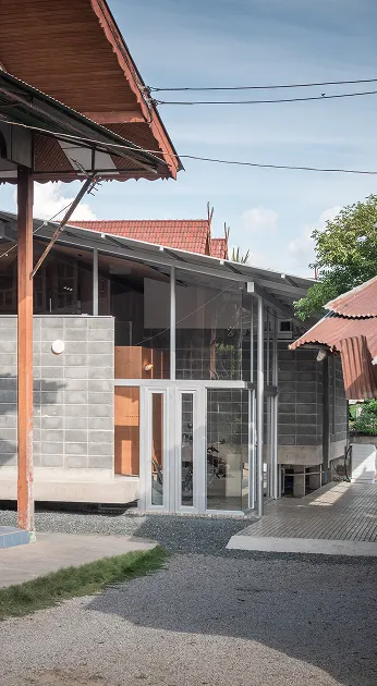Modern building with brick and glass facade, large windows, and slanted roofs, set against a blue sky with surrounding structures.