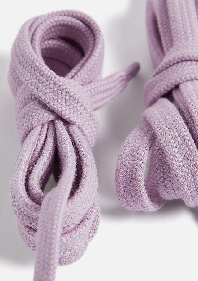 Two neatly coiled lavender shoelaces on a white background, showcasing their woven texture and soft pastel color.