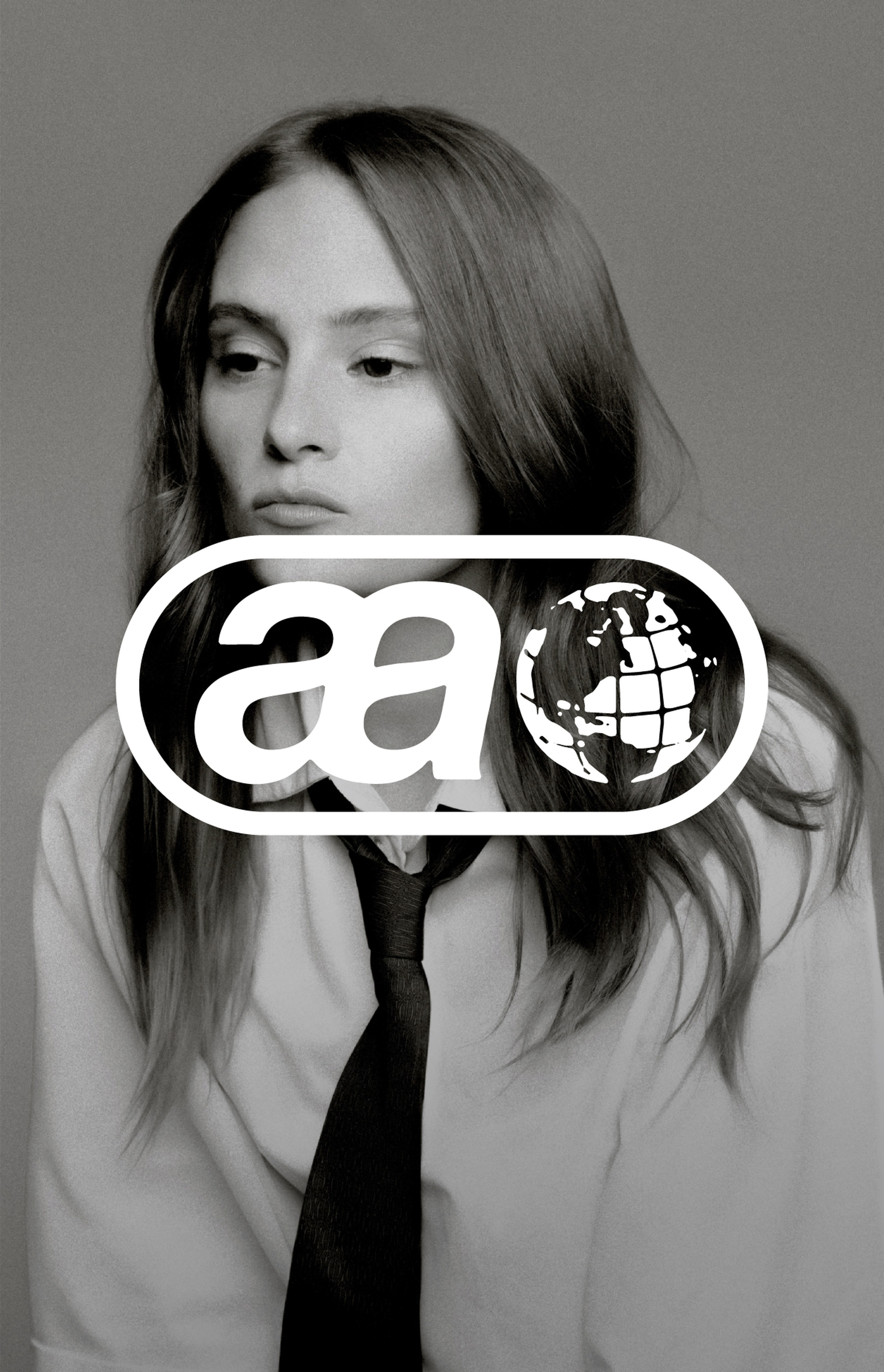 Black and white photo of a person with long hair wearing a shirt and tie. A globe logo with "aa" is overlaid on the image.