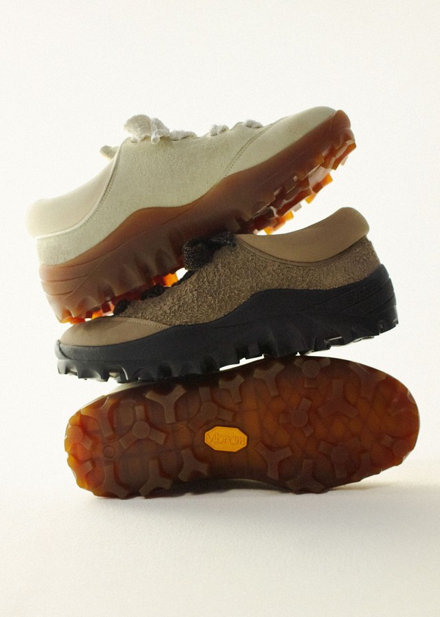 Three stacked sneakers with rugged soles, featuring different shades: beige, light brown, and dark brown, photographed against a white background.