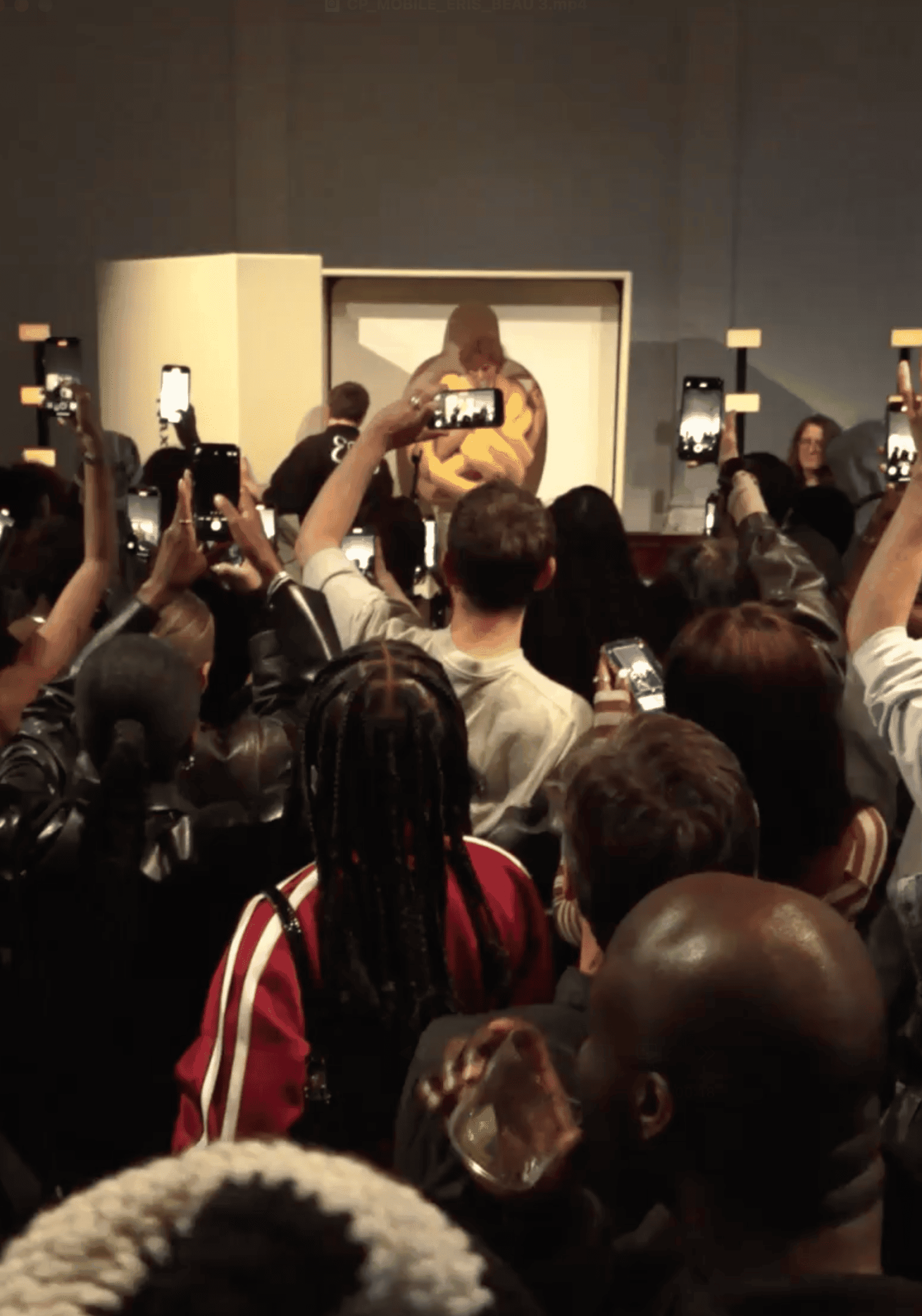 Crowd at an art auction capturing a framed painting being shredded with their phones.