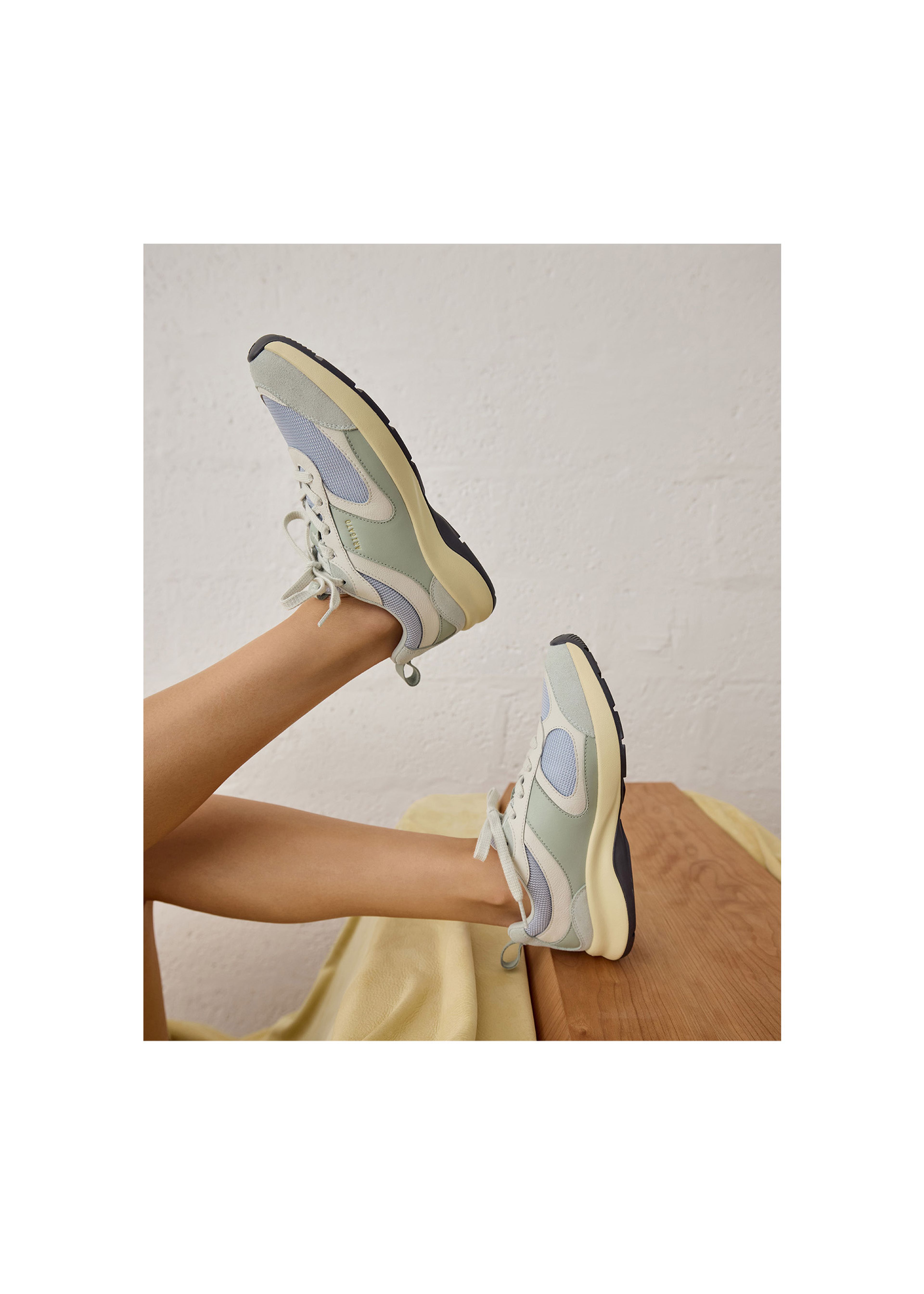 Person wearing pastel-colored sneakers with thick soles, legs raised against a neutral background.