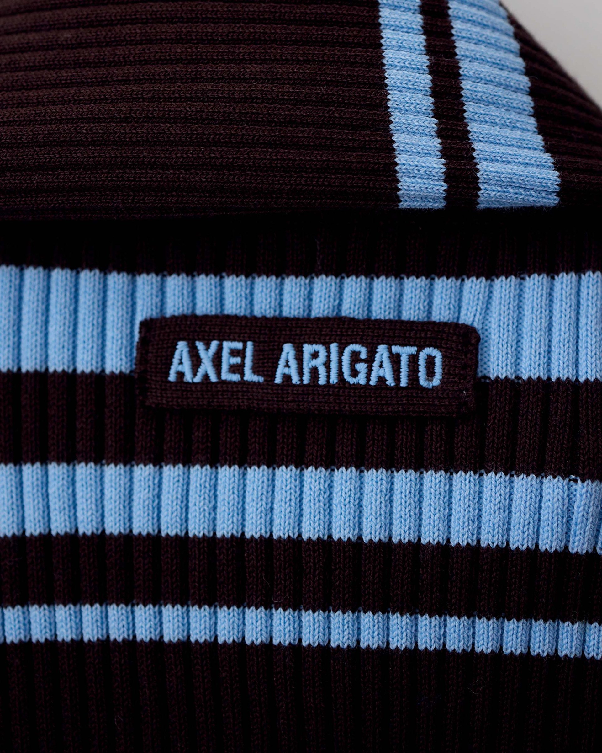 Close-up of a ribbed fabric with blue and black stripes and a label reading "Axel Arigato."
