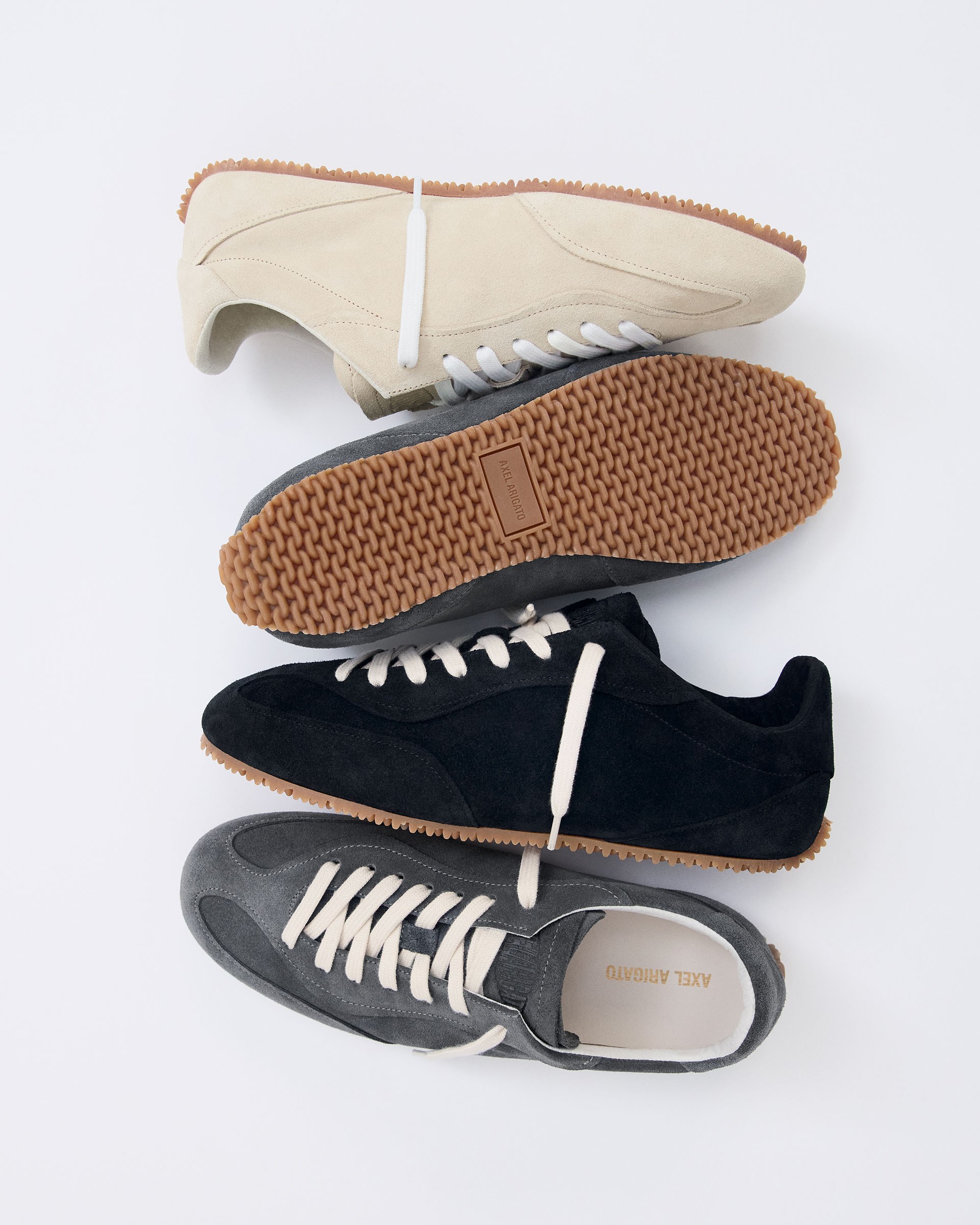Three pairs of sneakers in beige, black, and gray with gum soles, displayed on a white background.