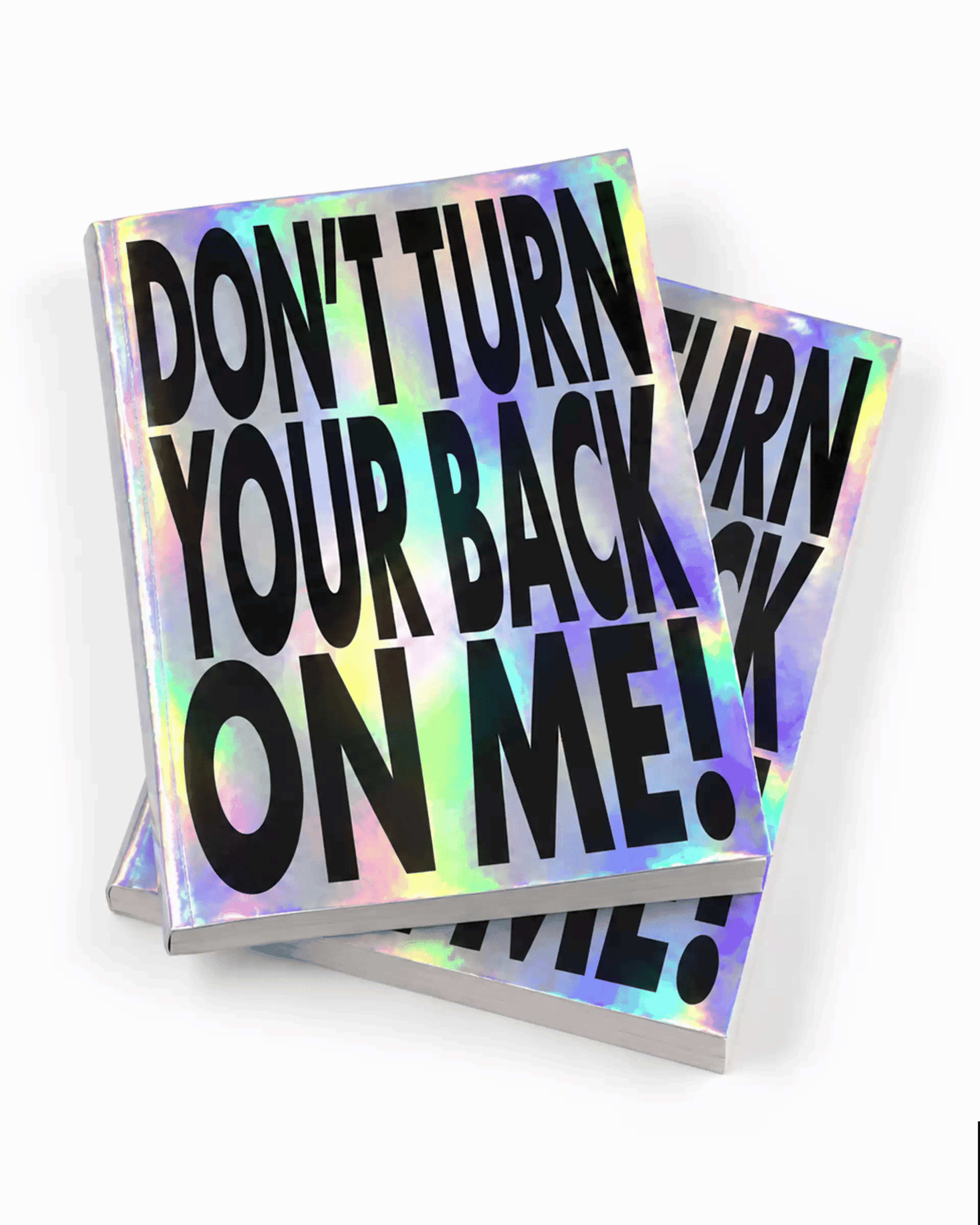 Two holographic books with bold black text reading "DON'T TURN YOUR BACK ON ME!" stacked slightly askew.