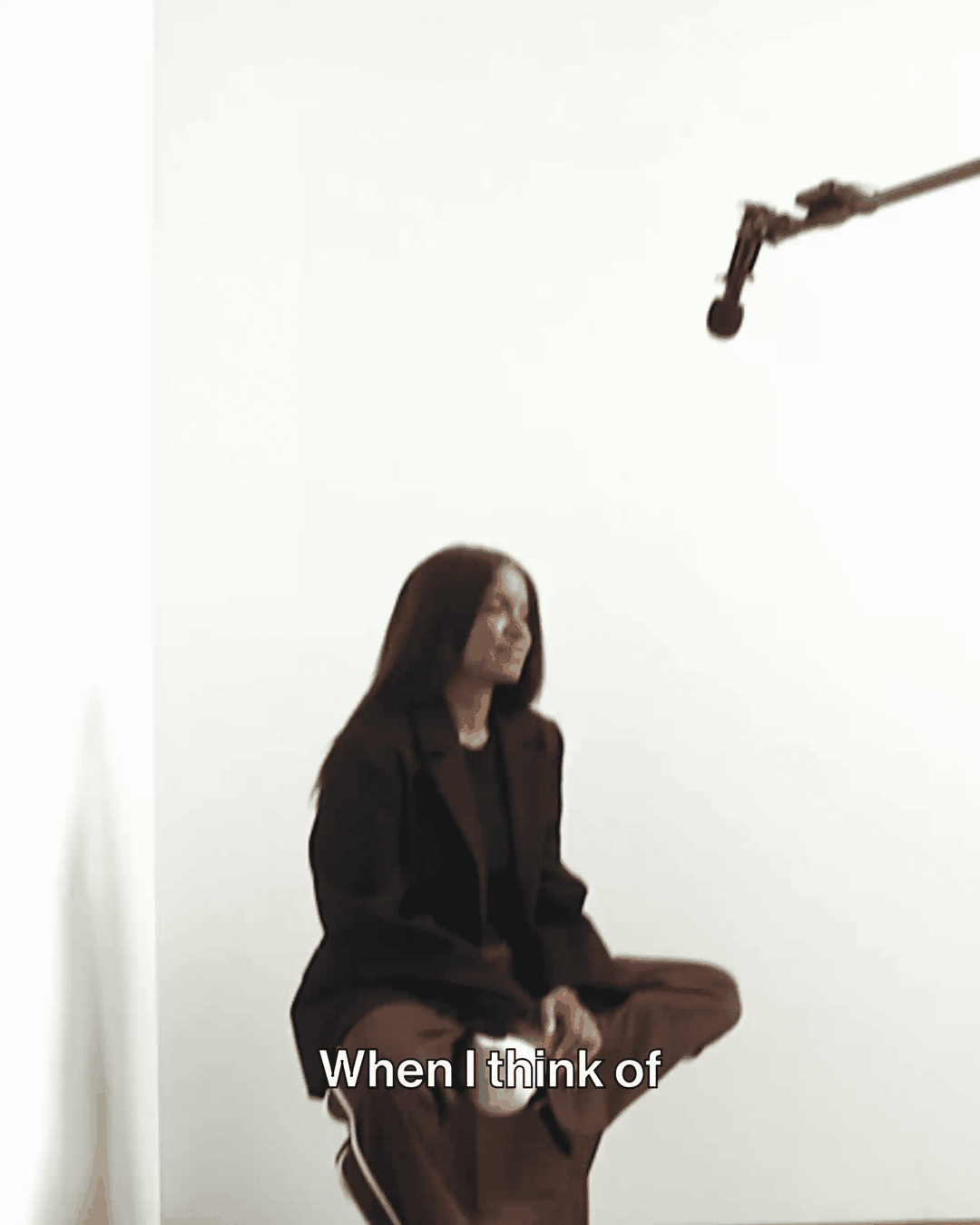 A person with long hair sits in a studio with a microphone overhead. The text reads, "When I think of."