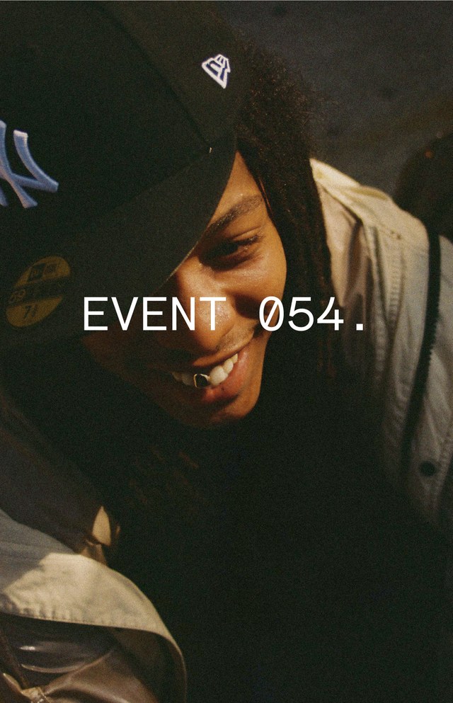 Person wearing a cap with a New York Yankees logo, smiling, with "EVENT 054." text overlay.