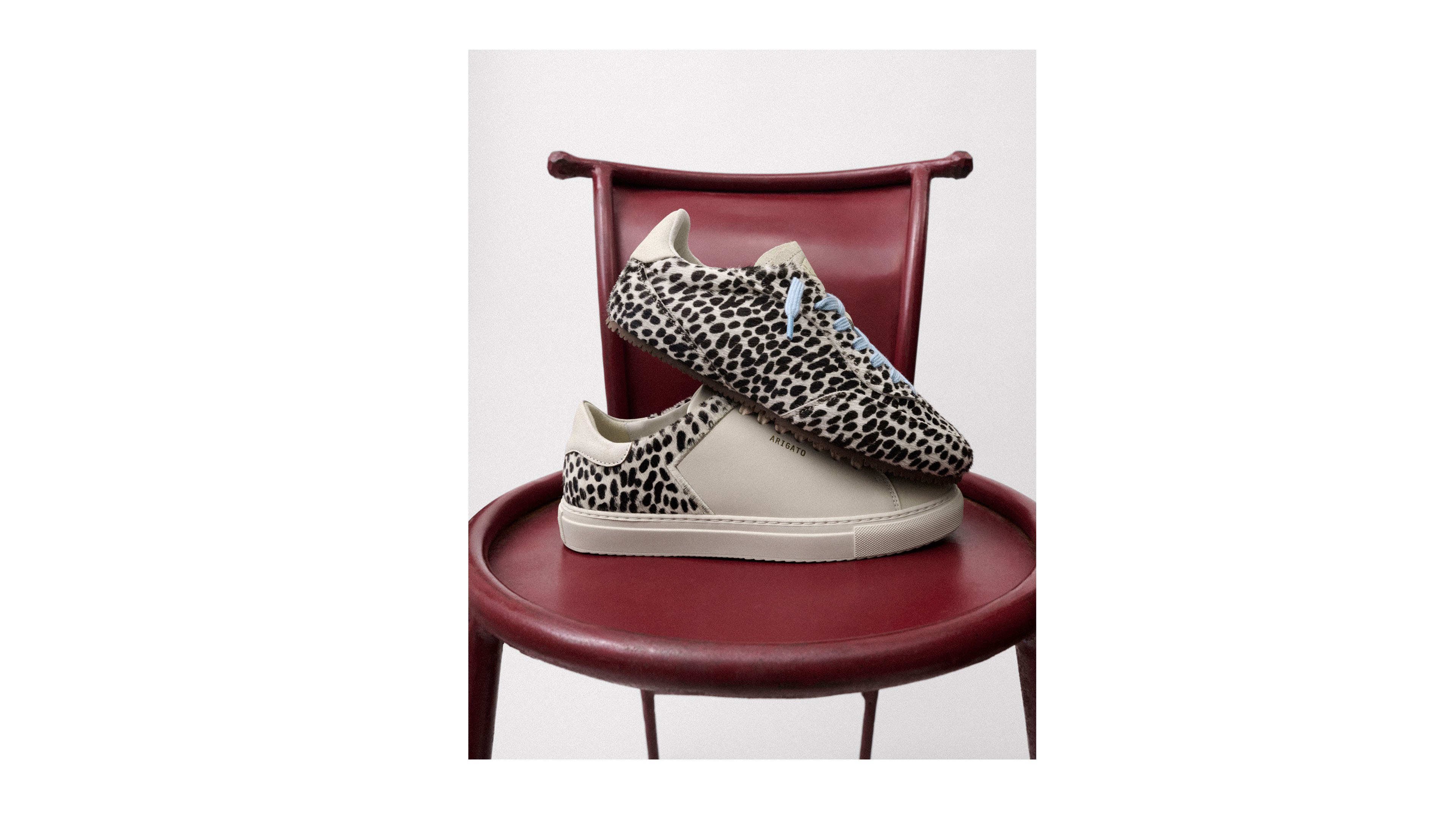 Leopard print sneakers with beige soles on a red chair against a white background.