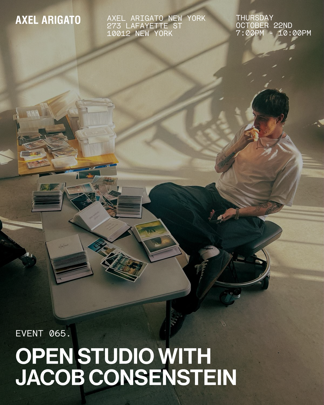 A person sitting in a sunlit room with tables covered in books and papers. Event information for "Open Studio with Jacob Consenstein" is visible.