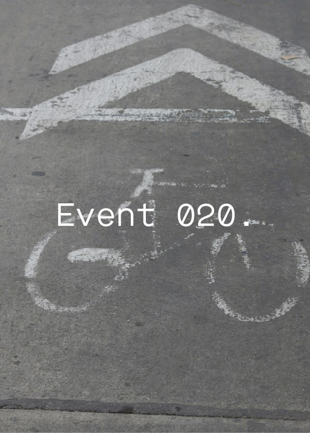 Bike lane symbol on asphalt road with white arrows and the text "Event 020."