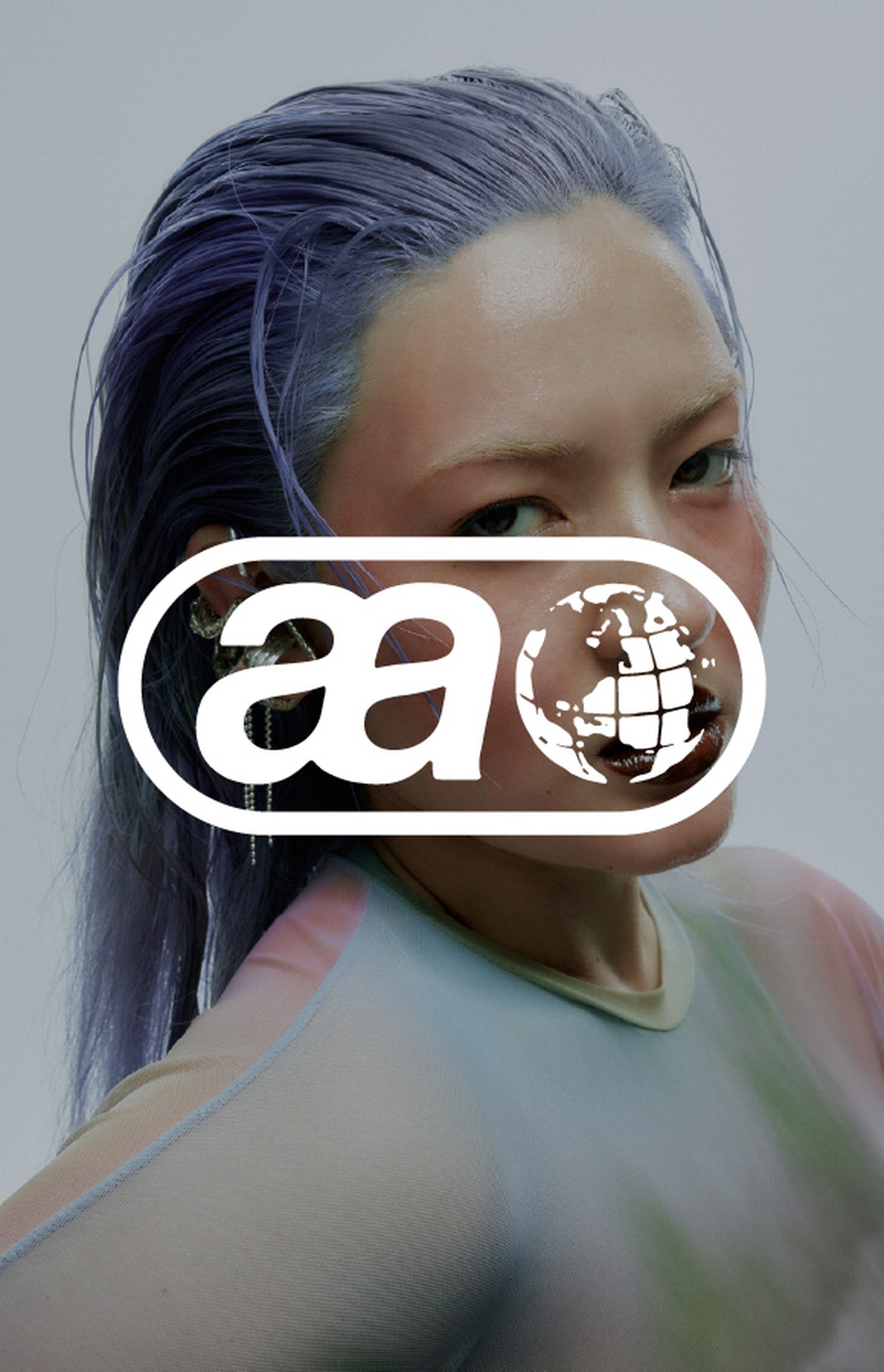Person with slicked-back purple hair in a colorful outfit, partially obscured by a white logo featuring stylized letters and a globe.