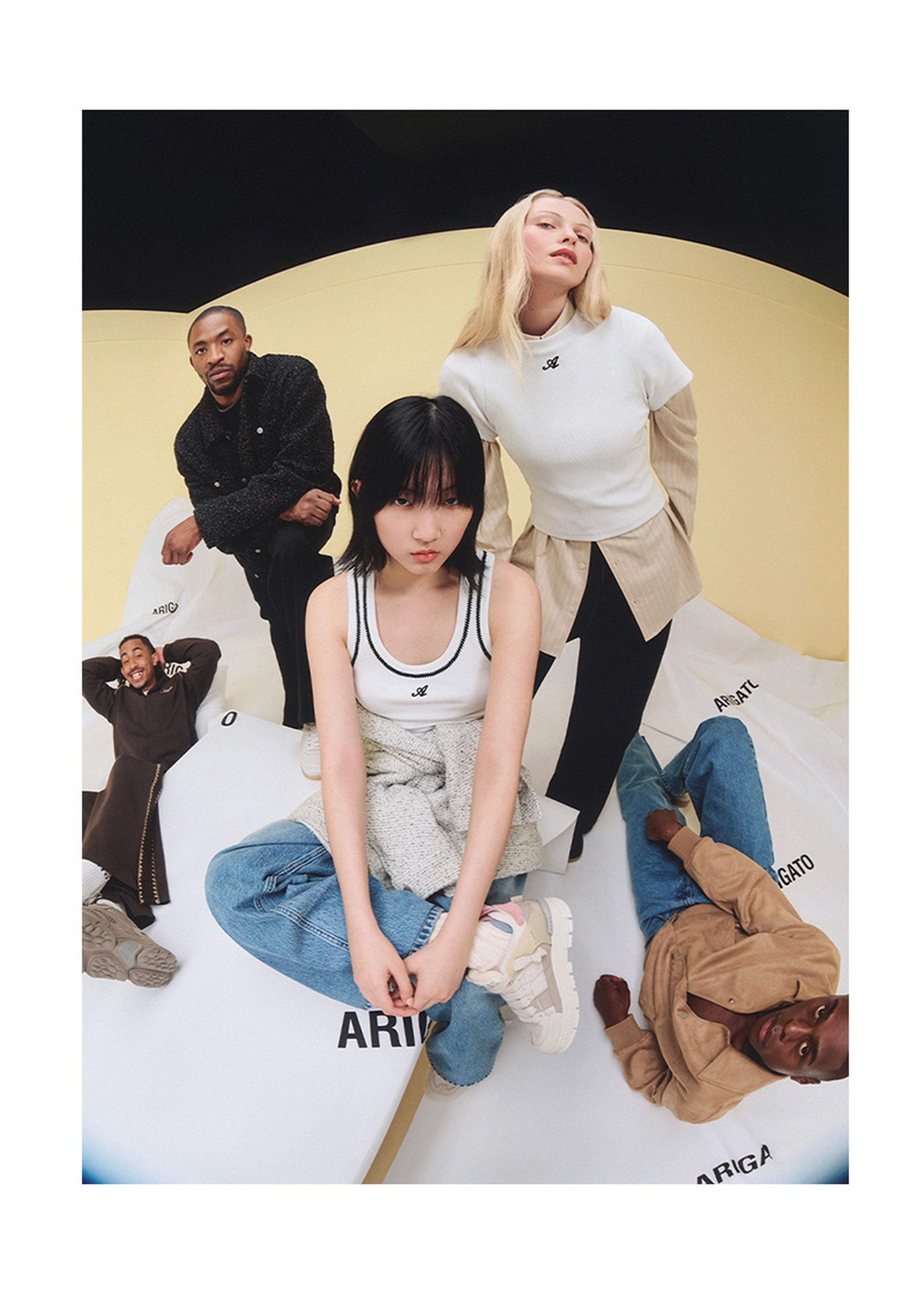Four models pose on a branded surface, wearing casual and sporty outfits. The scene has a modern, fashion-forward vibe.