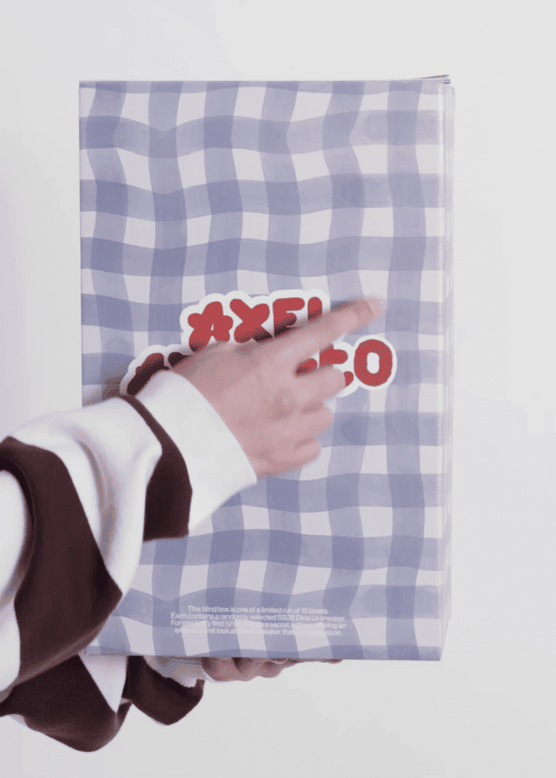 A person in a striped sweater points at a wavy blue and white patterned box with red text.