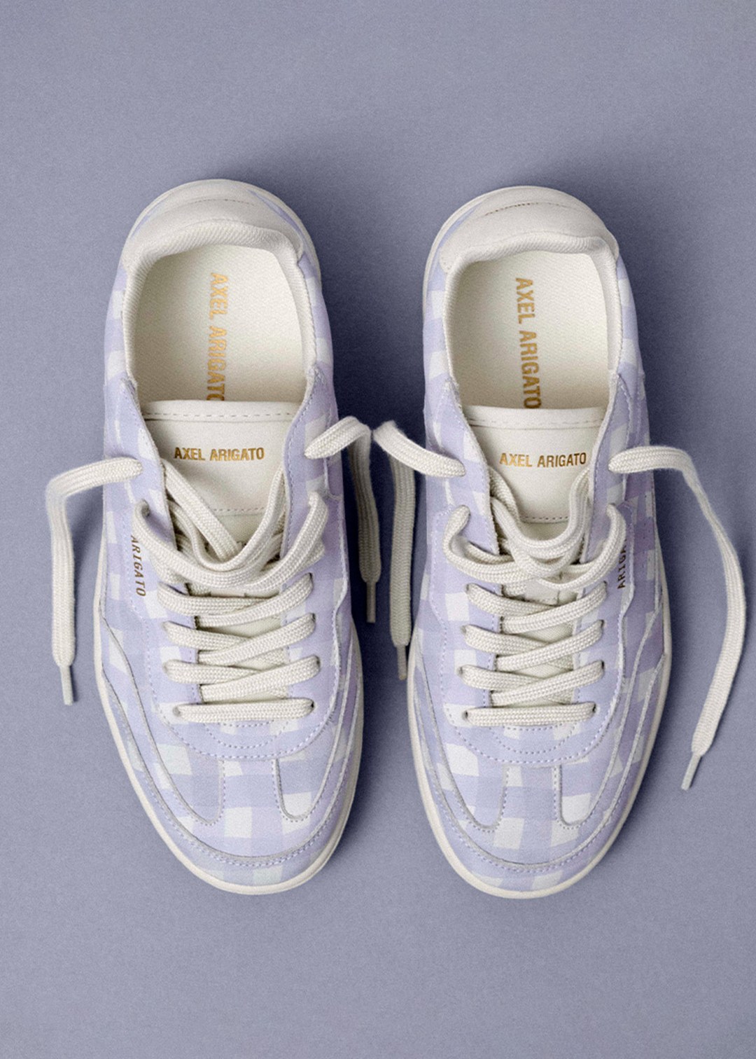 Top view of light purple checkered sneakers with white laces on a purple background.