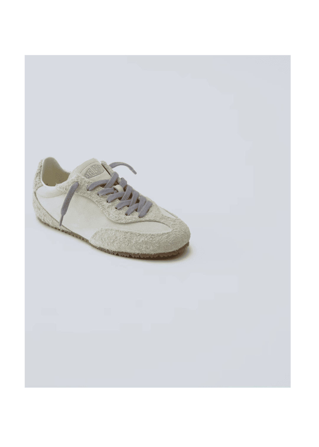 A single beige sneaker with light gray laces on a white background, featuring a textured outer layer and a sleek design.
