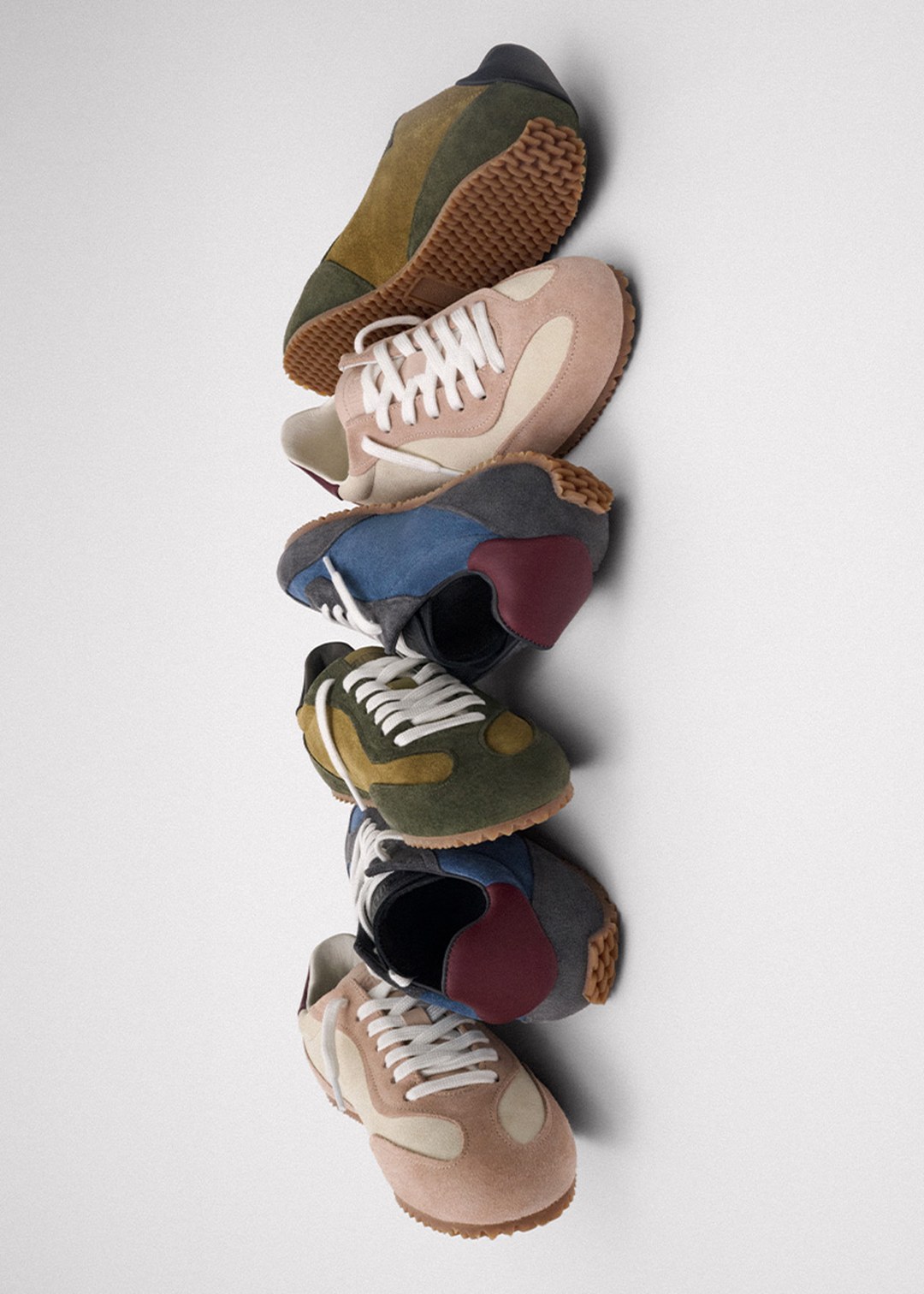 A vertical stack of five pairs of colorful vintage sneakers with various designs against a plain background.