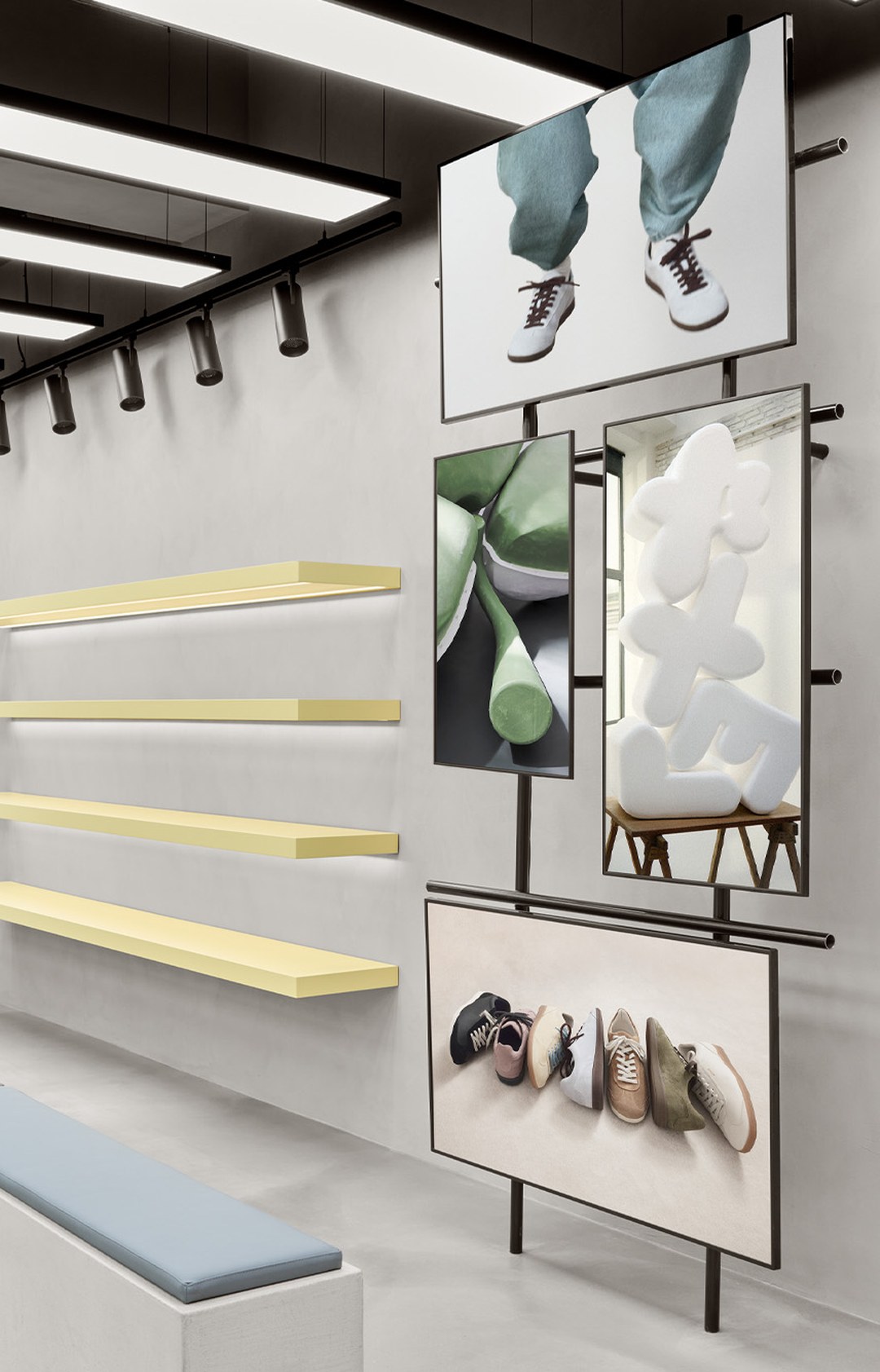 Modern interior with wall-mounted art, showcasing shoes and abstract designs, beside minimalistic yellow shelves and a gray bench.