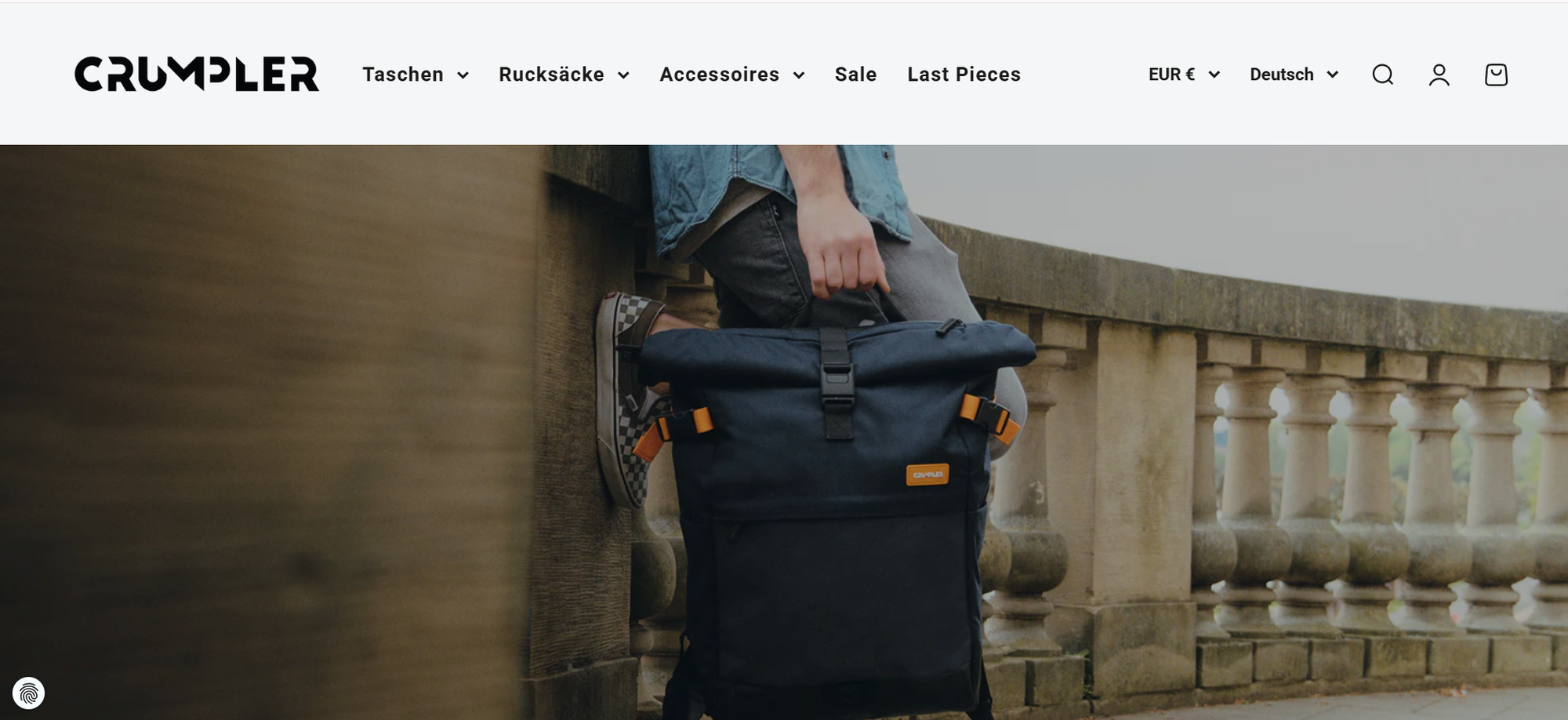 Person sitting on stone steps holding a navy blue Crumpler backpack; website header displays categories like bags and accessories.