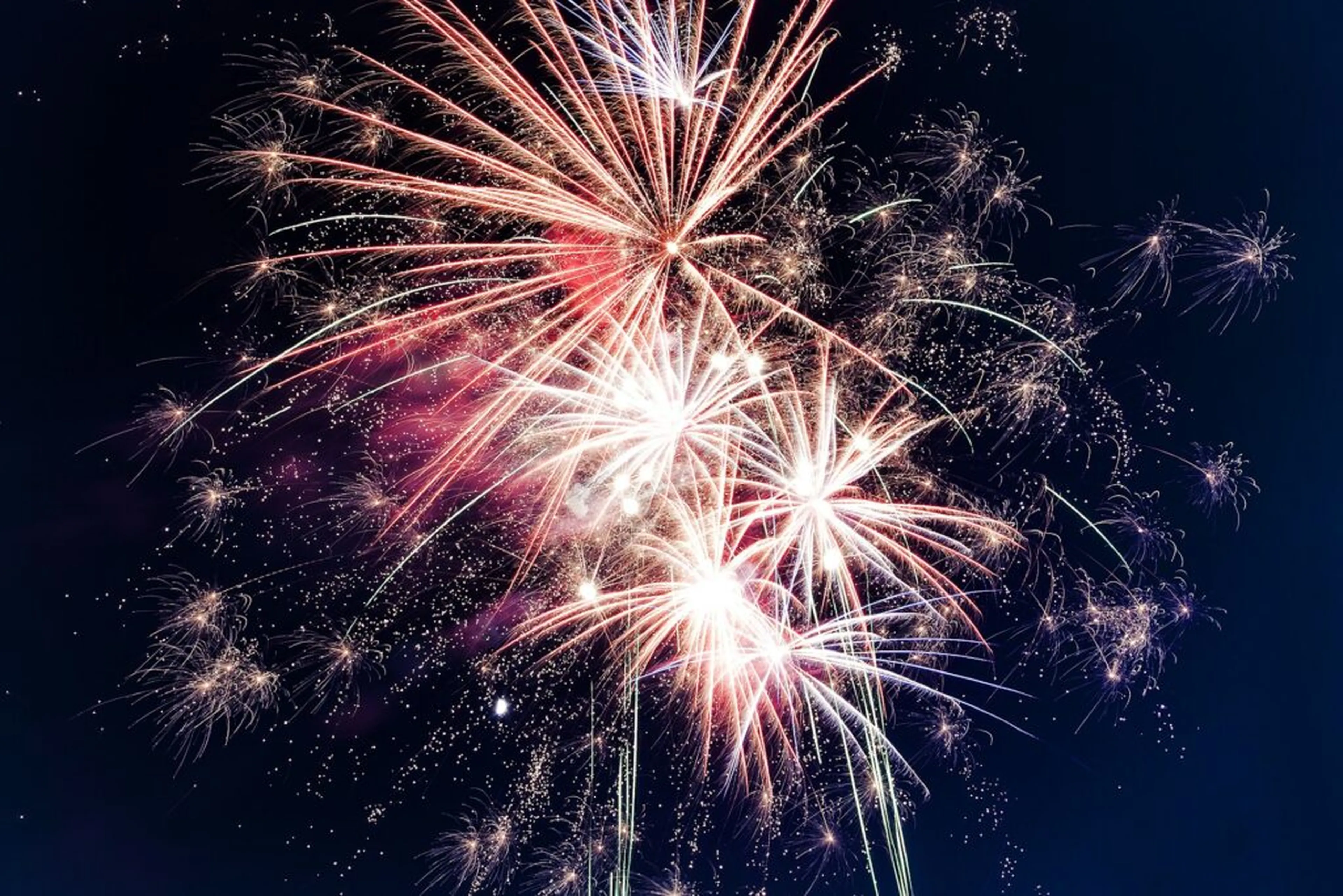 Colorful fireworks explode against a dark night sky, creating a bright and festive display of light and sparks.
