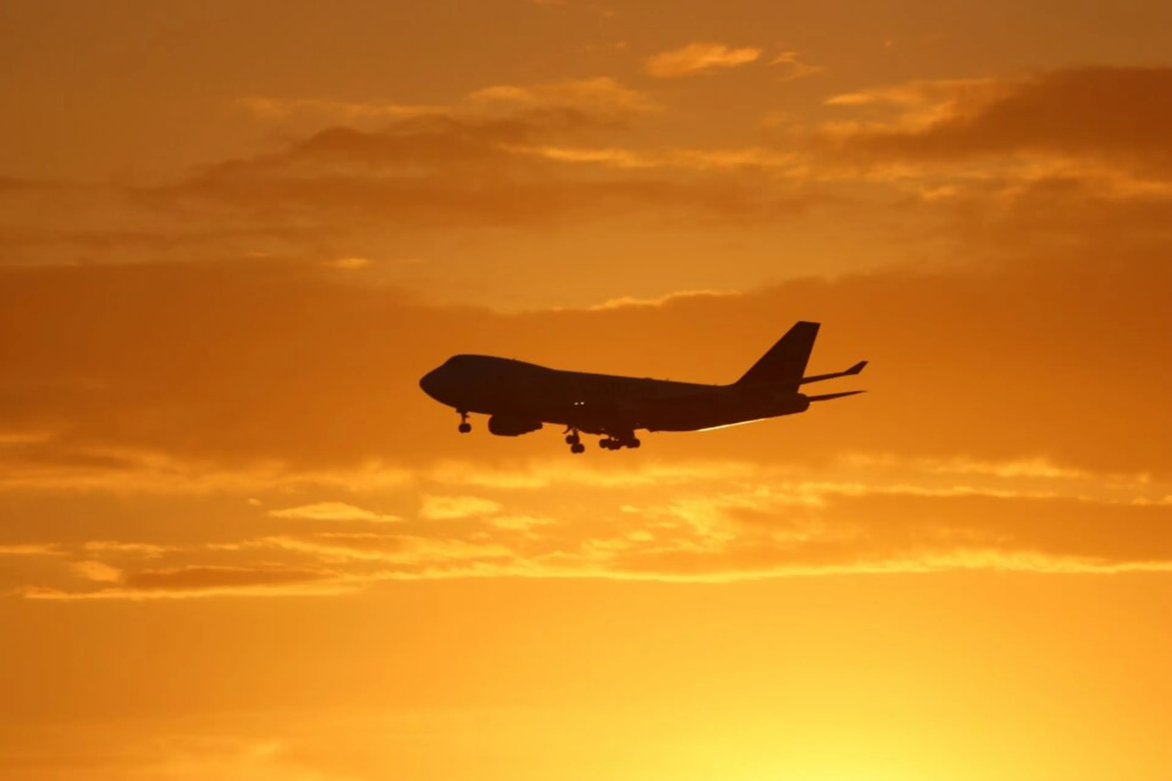 airplane flying against a sunset background