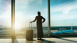 Woman looking out over airport runway during sunrise