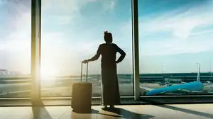 Woman looking out over airport runway during sunrise