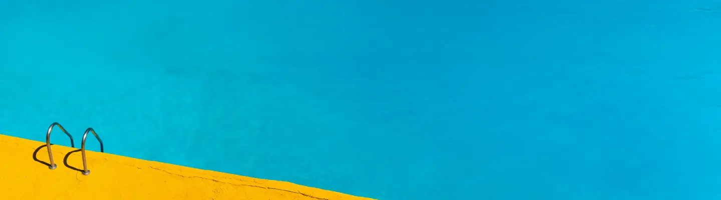 Bright blue swimming pool with a vibrant yellow deck and a metal ladder, creating a striking color contrast.