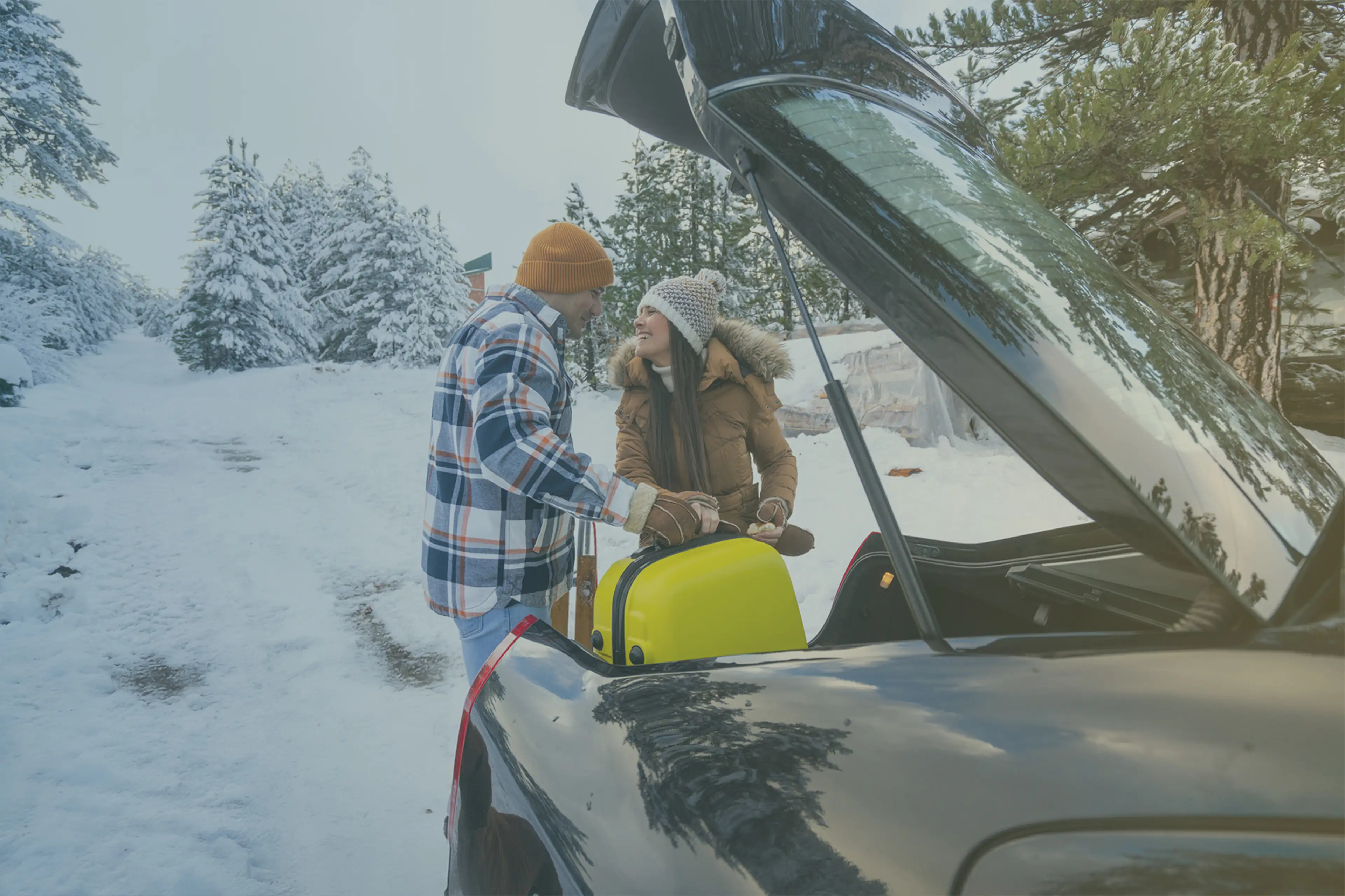 couple at boot of car with suitcase in winter