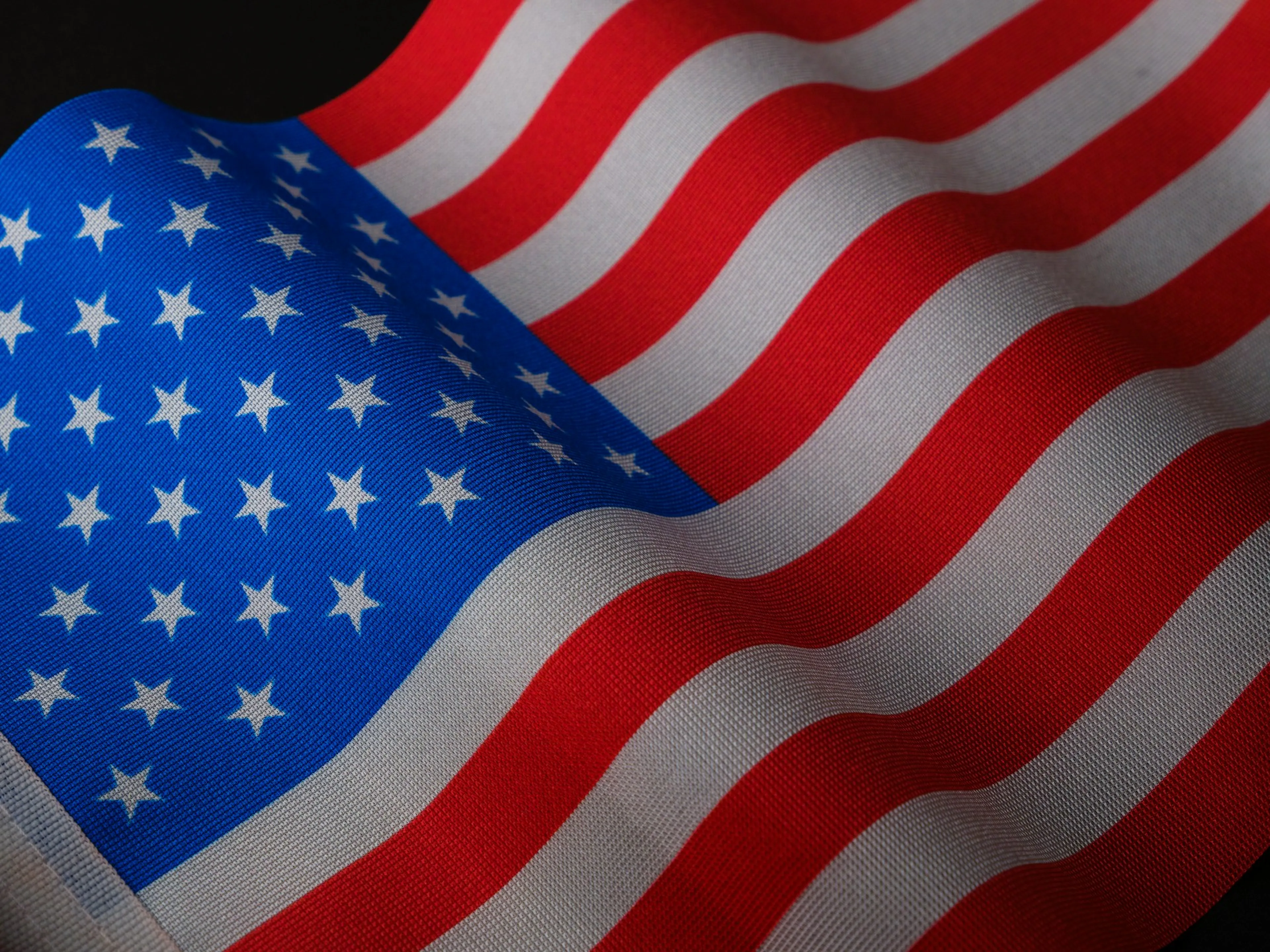 Close-up of a waving American flag, showcasing the stars and stripes pattern in vivid red, white, and blue colors.