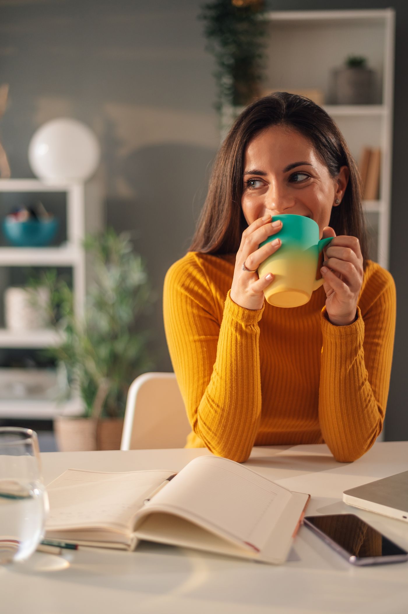 Junge und vitale Frau mit Tasse am Schreibtisch
