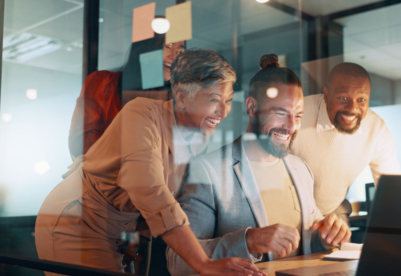 Gut gelauntes Team im Büro schaut gemeinsam auf einen Bildschirm