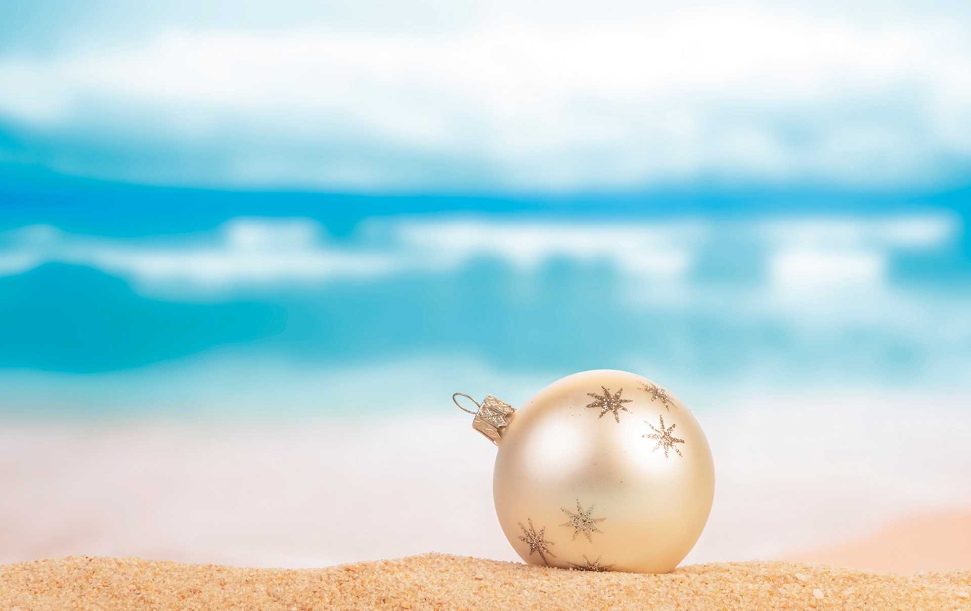 Christmas ball on yellow sand and sea background