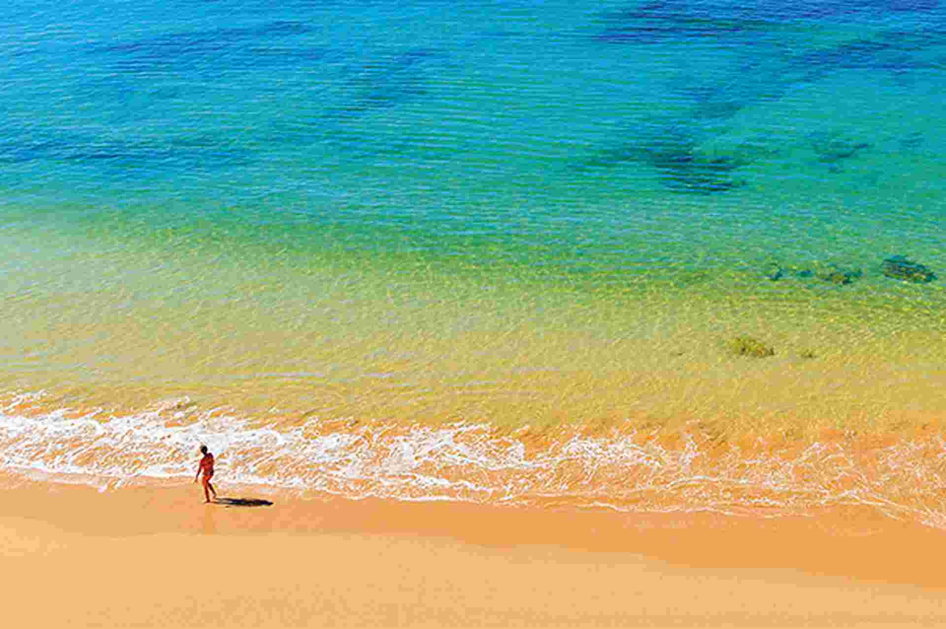 Woman walking along a beach, Portugal.