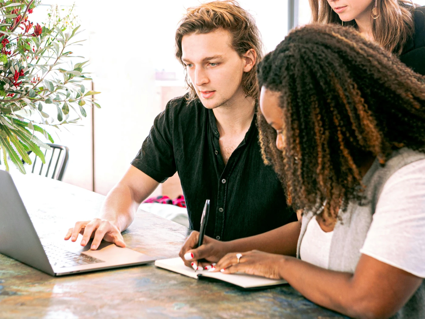 People looking at laptop and a person writing notes