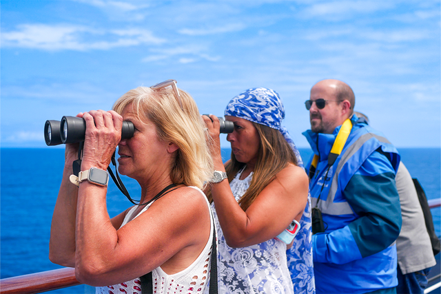 Kerrie Ann and Julie on a ship deck using binoculars to view the ocean