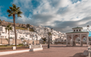 A scenic view of the Moroccan town, Tetouan with white buildings on a hillside, palm trees, and a traditional archway.