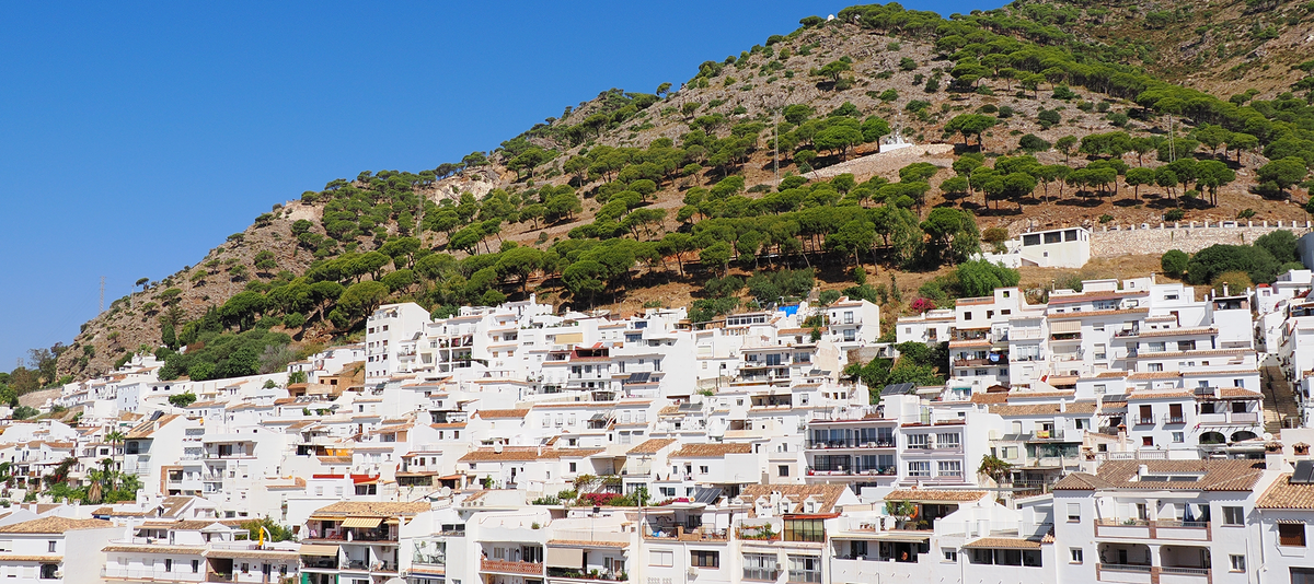 Hillside village called Mijas in Malaga, Spain with white buildings on a slope under a clear blue sky.