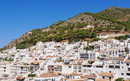 Hillside village called Mijas in Malaga, Spain with white buildings on a slope under a clear blue sky.