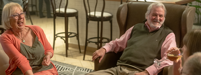 Smiling solo guest chatting with fellow travellers in a lounge