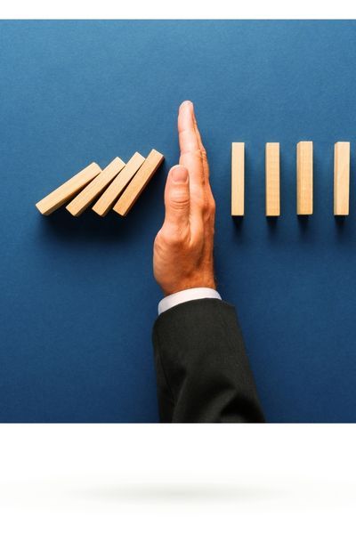 Hand stoppt umfallende Bausteine