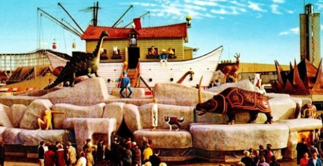 Crowd gathered at a vintage amusement park with a large Noah's Ark attraction, surrounded by animal sculptures and vibrant 1960s clothing.