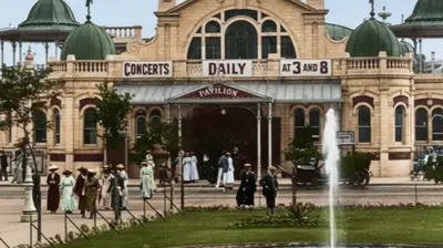 Historic pavilion hosting daily concerts at 3 and 8, with people in period attire walking nearby and a fountain in the foreground.