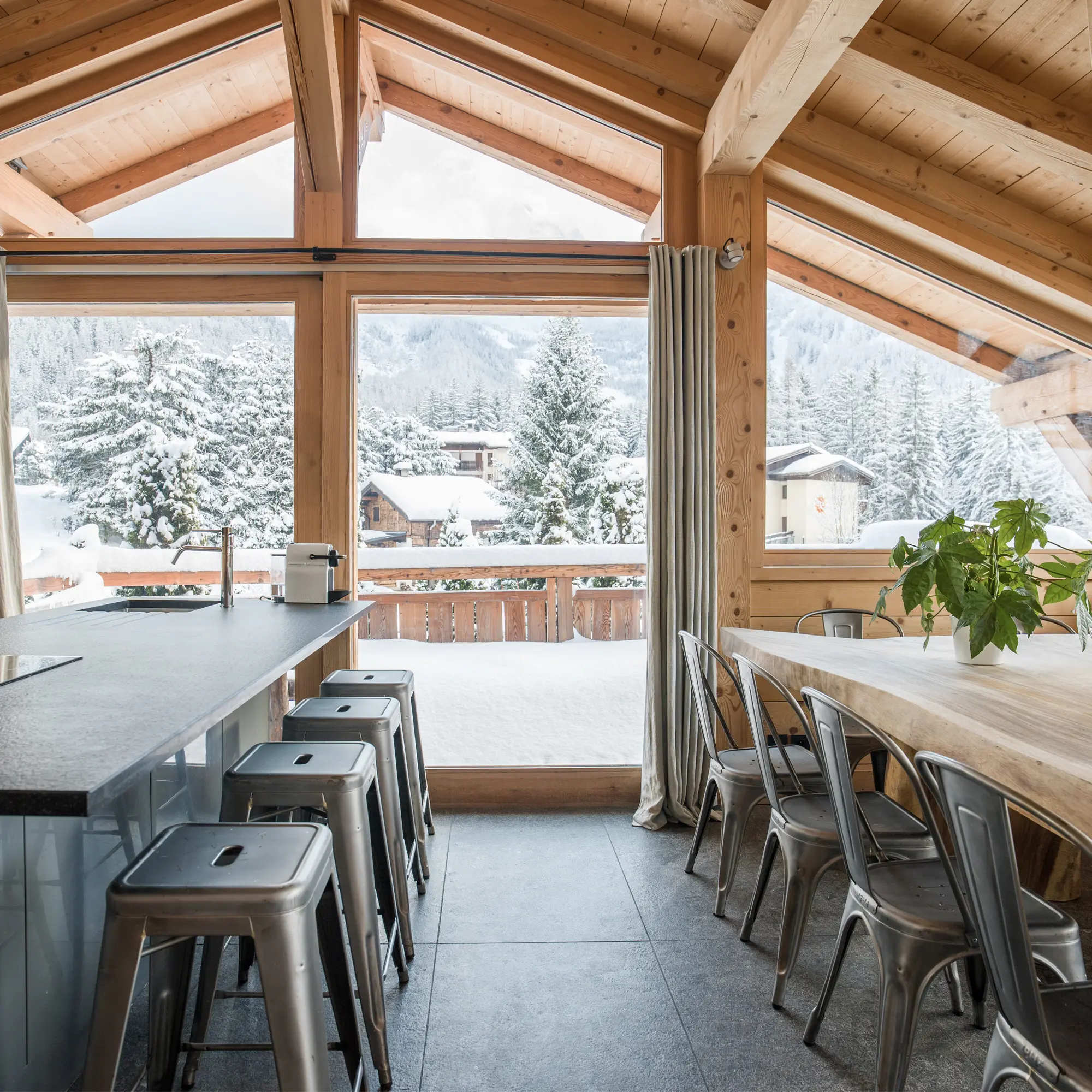 Location de Chalets Chamonix - Chalet Granit - cuisine et grande table face aux baies vitrées et au paysage enneigé