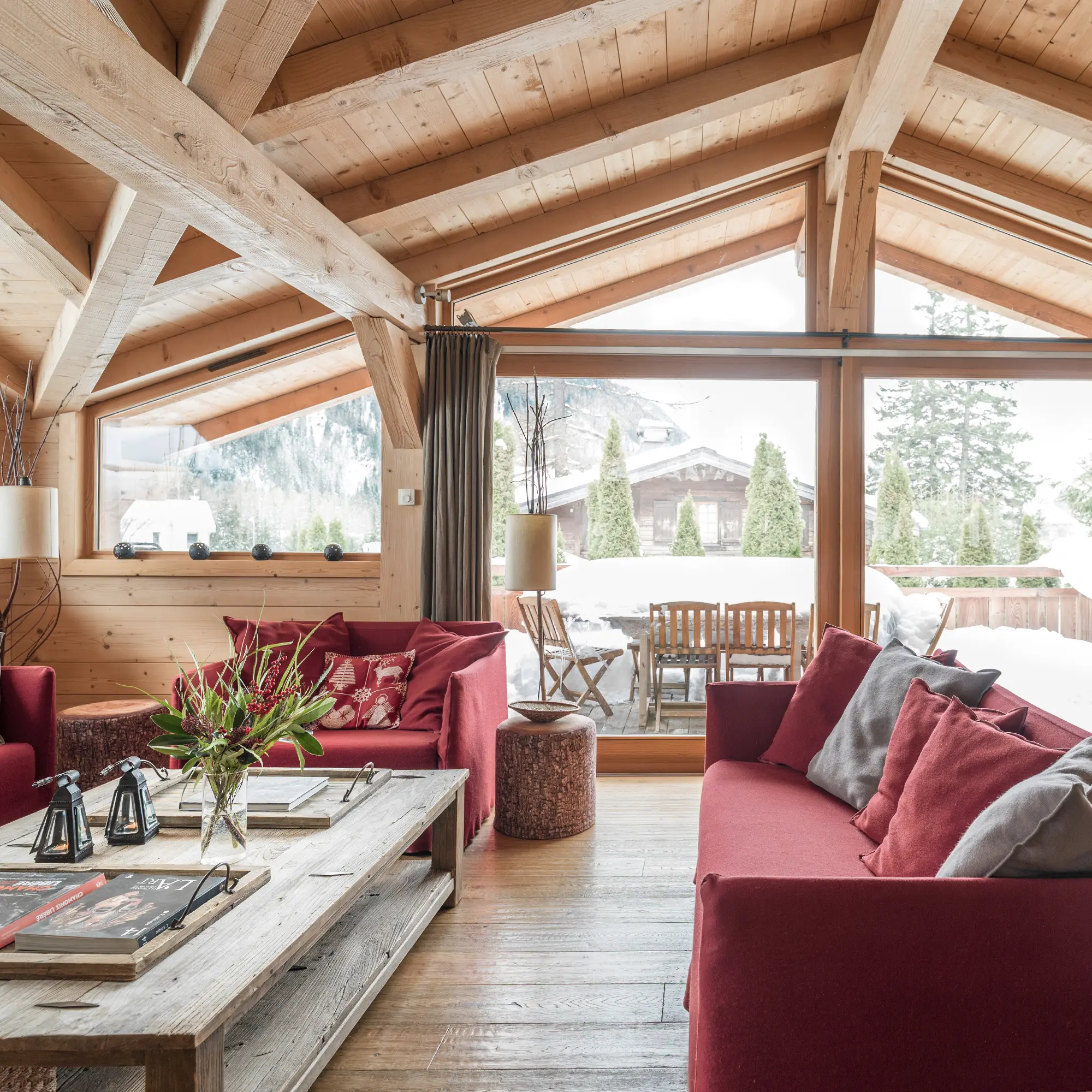 Location de Chalets Chamonix - Chalet Ardoise - salon aux canapés bordeaux sous charpente, baies vitrées sur la neige