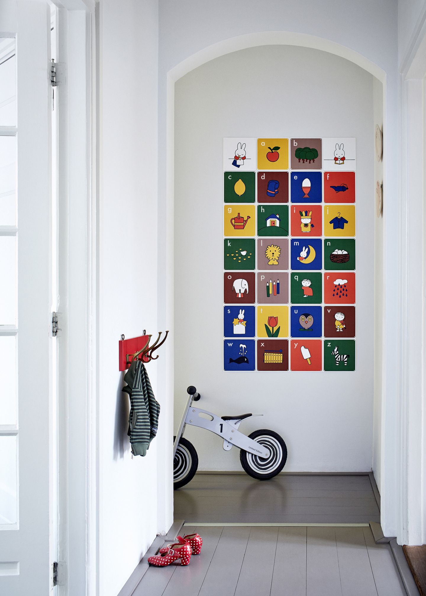 IXXI of a Miffy alphabet in a bright hallway, above a balance bike and a small red coat rack