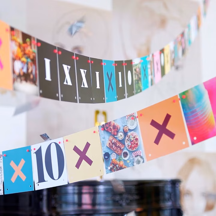 Loose IXXI cards strung as a garland in an arc, letters and photographs mixed together
