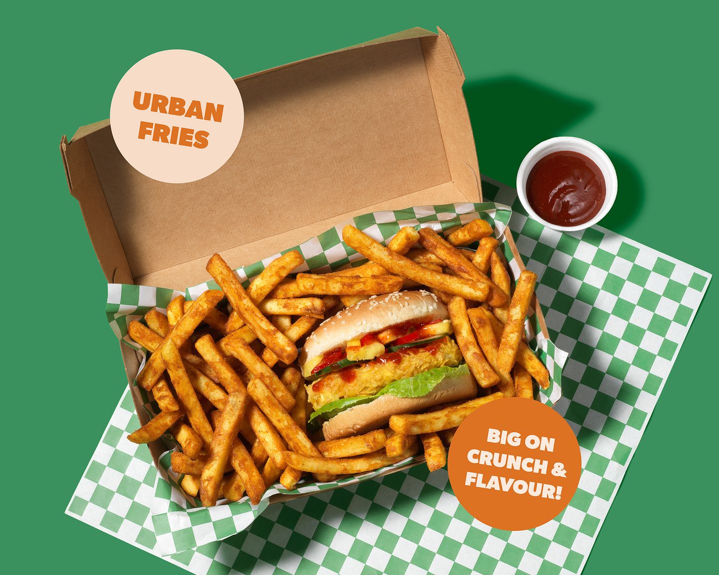 Takeout box of Urban Fries surrounding a burger on green-checked paper, with a cup of ketchup and an "Urban Fries" promo badge.