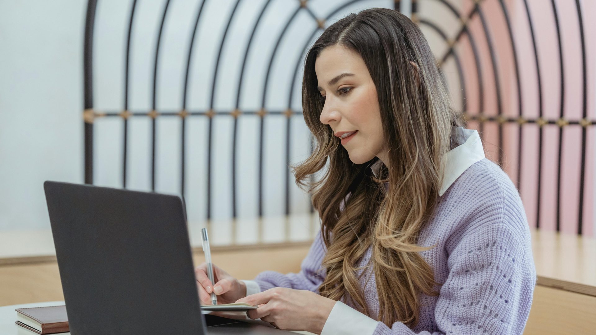 Femme concentrée prenant des notes pour apprendre l'anglais sur un ordinateur portable.