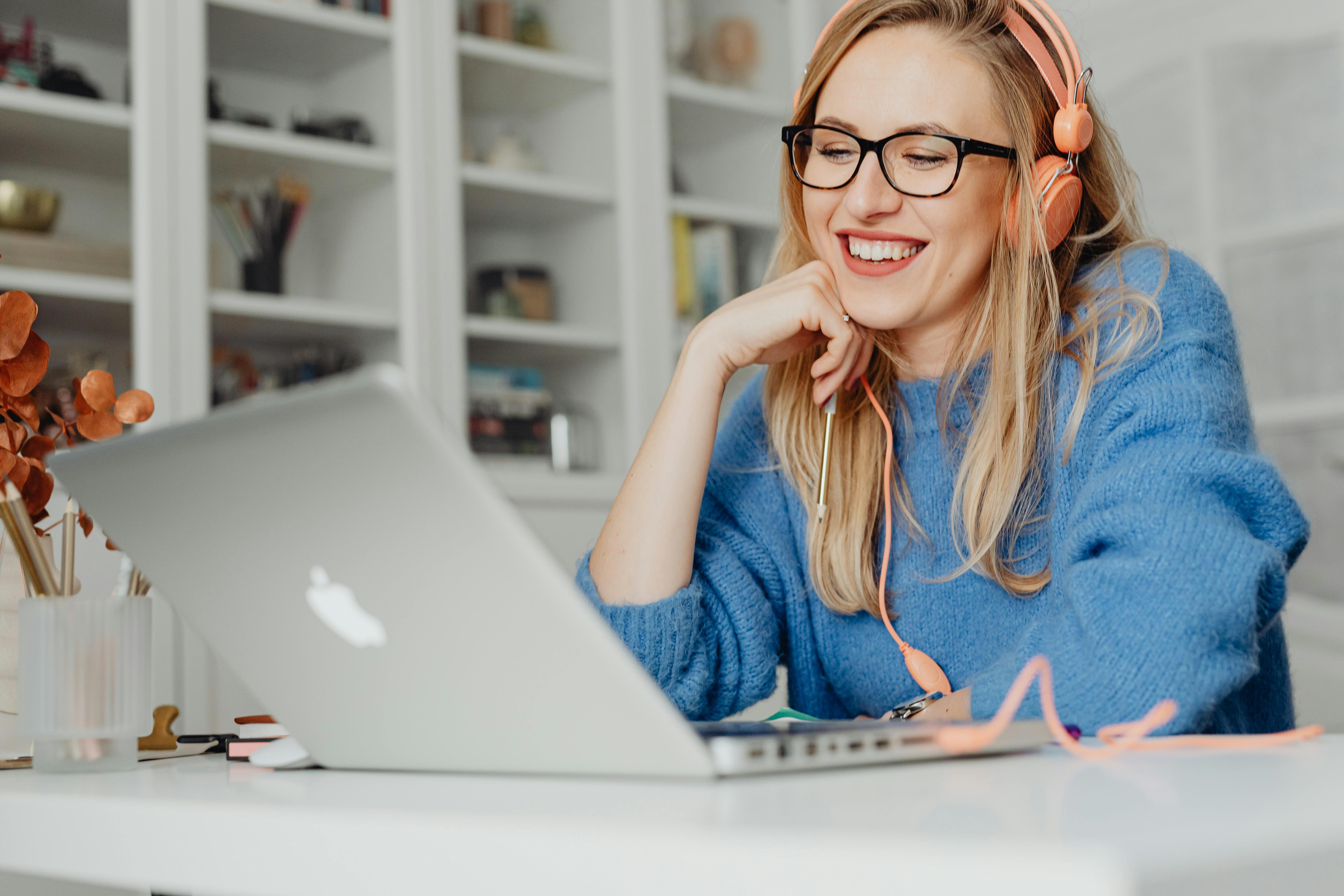 Femme souriante avec un casque audio participant à un cours d'anglais en ligne sur son ordinateur portable
