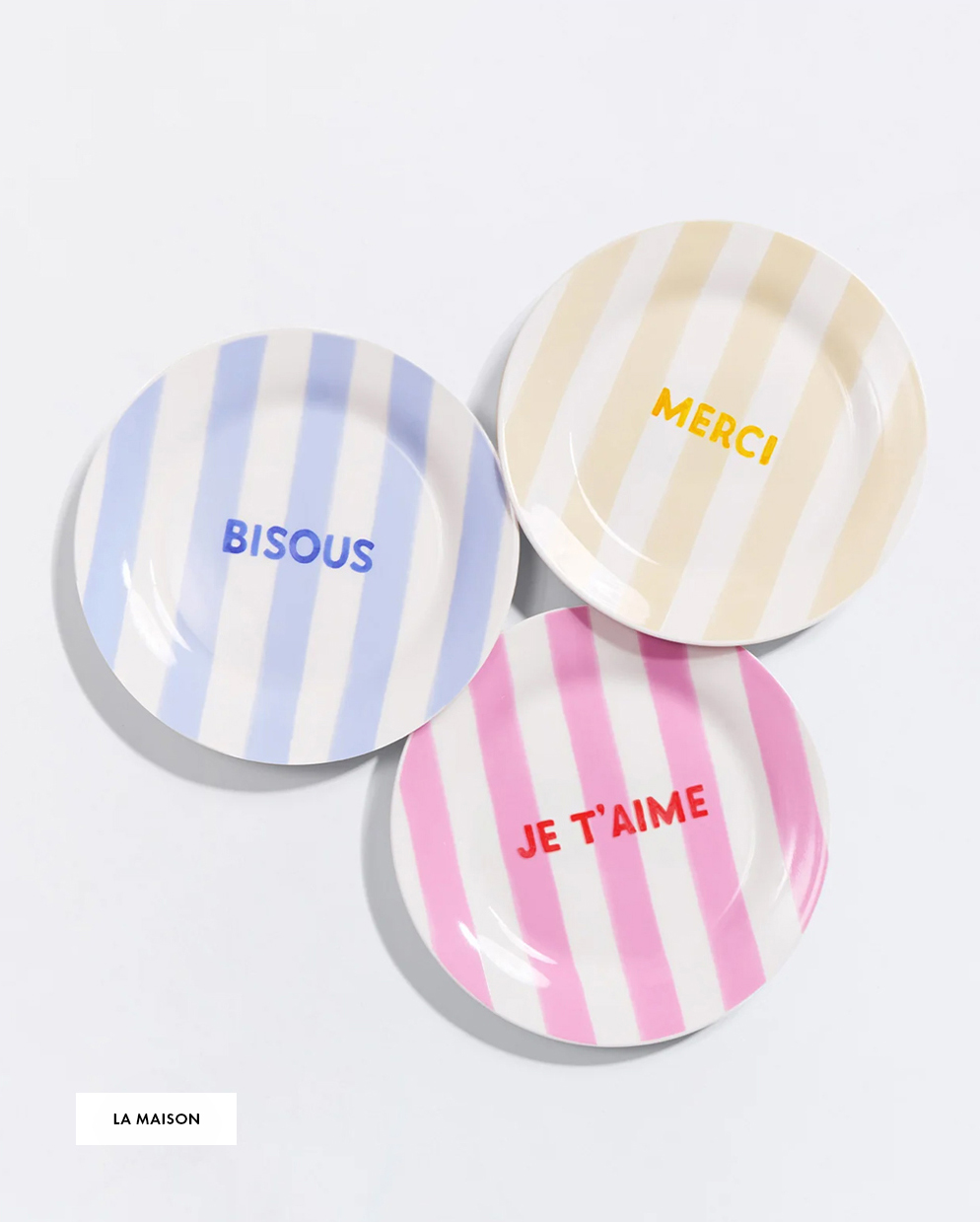Three striped plates with French words: "BISOUS" in blue, "MERCI" in yellow, "JE T